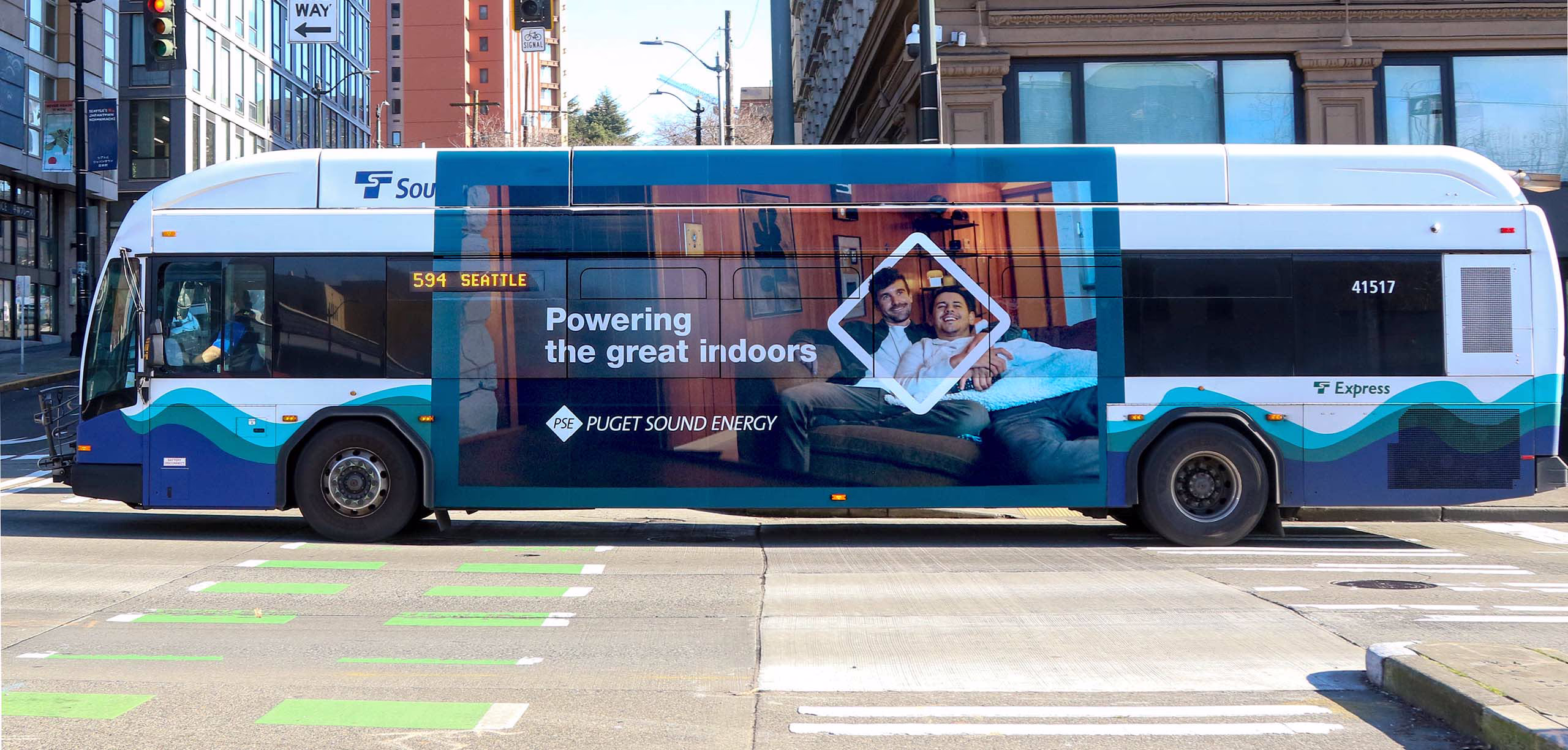 Sound Transit bus with a PSE ad of male couple on couch. Headline: Powering the great indoors